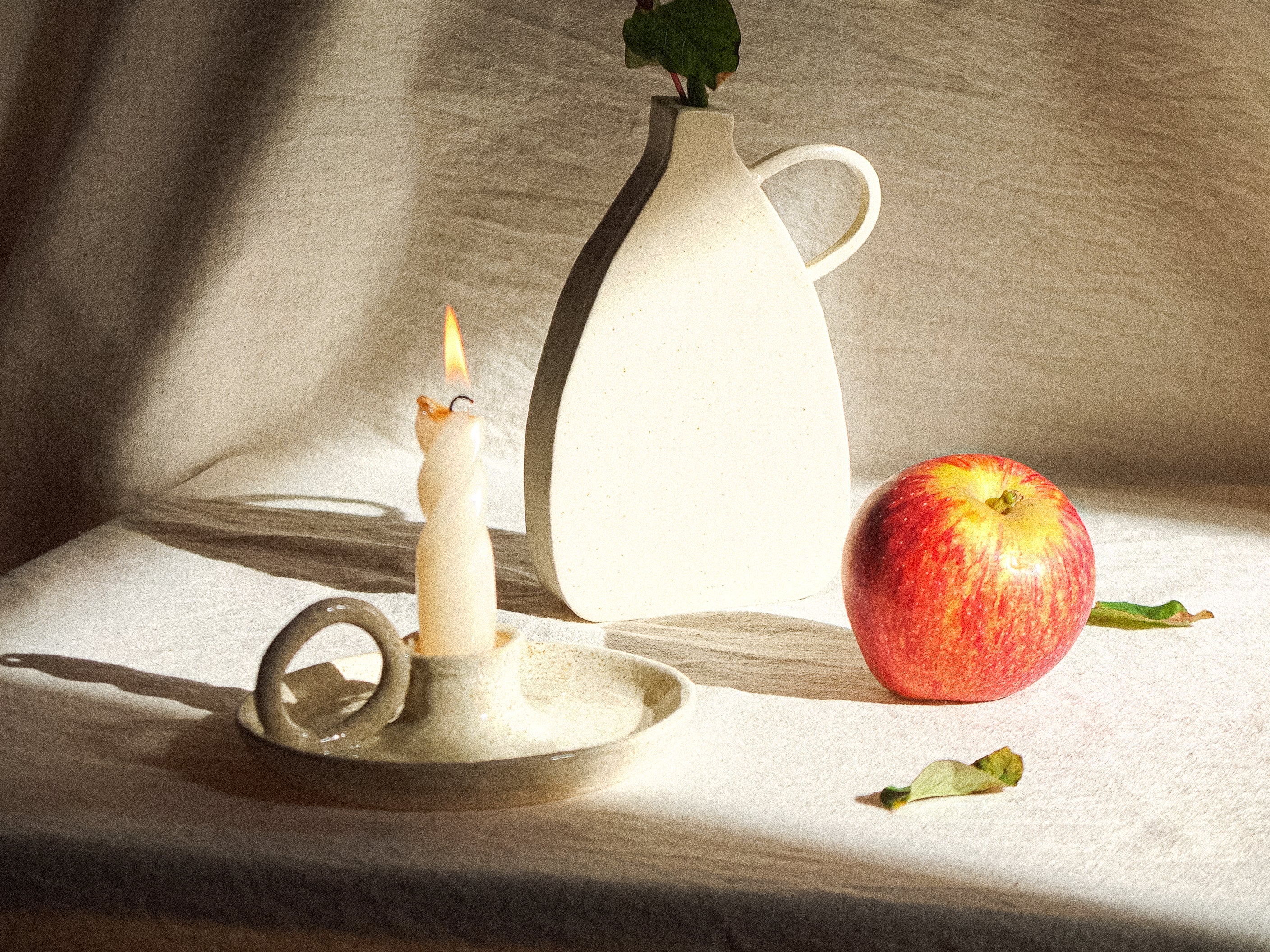 Nature morte composée d'une bougie, un bougeoir, un vase et une pomme