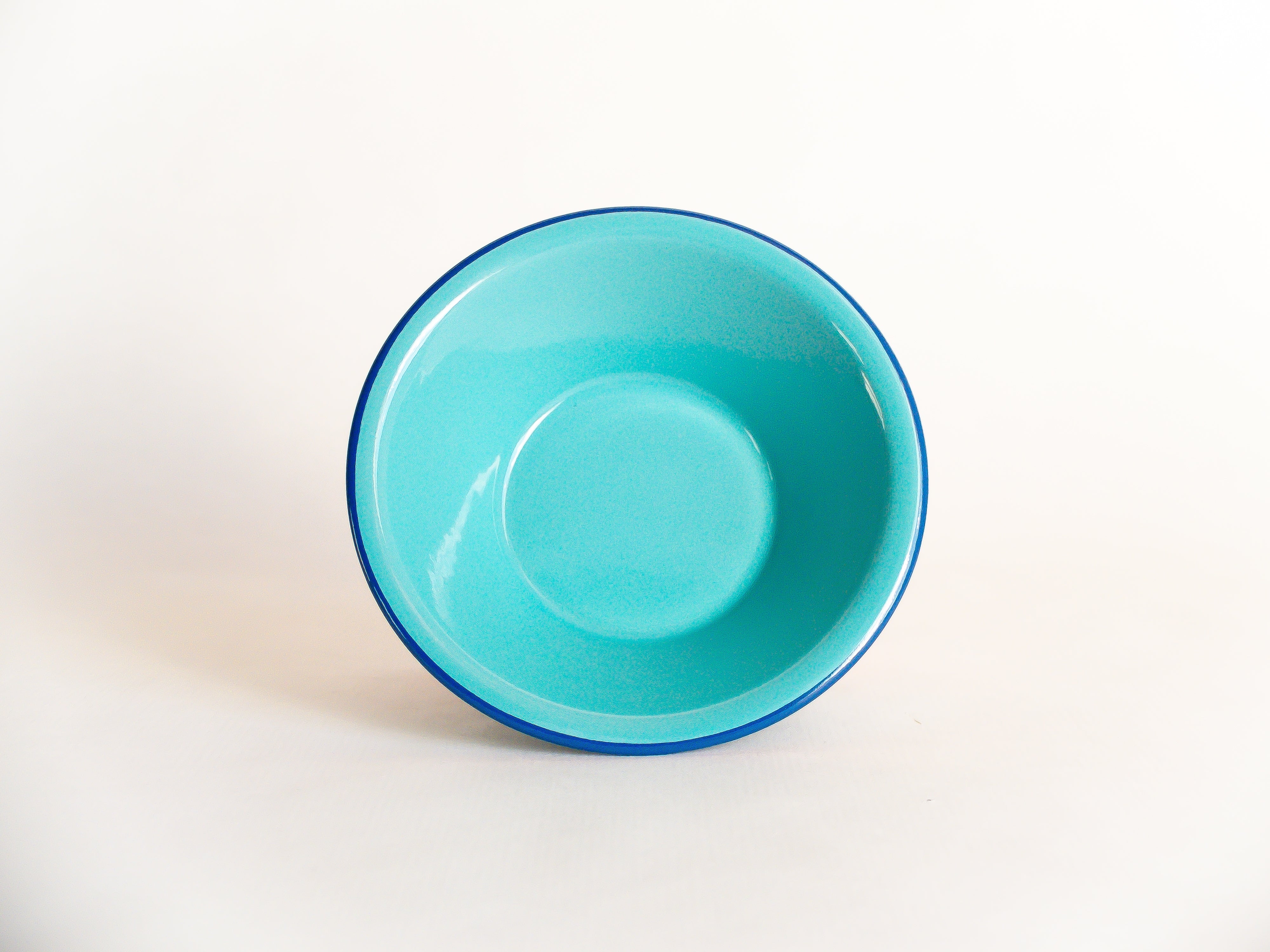 Petit bol en émail incassable turquoise à rebord bleu foncé. Collection de vaisselle nomade