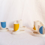 Ensemble à café, composé de tasses et coupelles aux formes organiques et couleurs pétillantes.